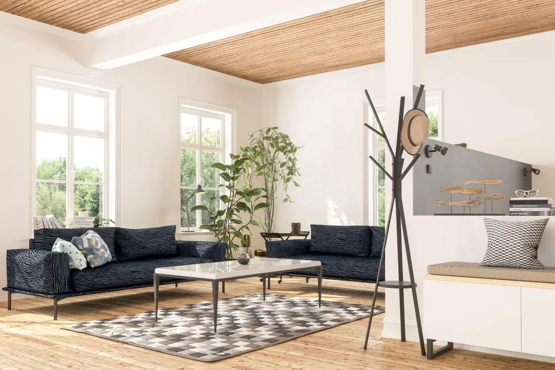 Jasny salon z drewnianym sufitem, granatową sofą i wieszakiem stojącym