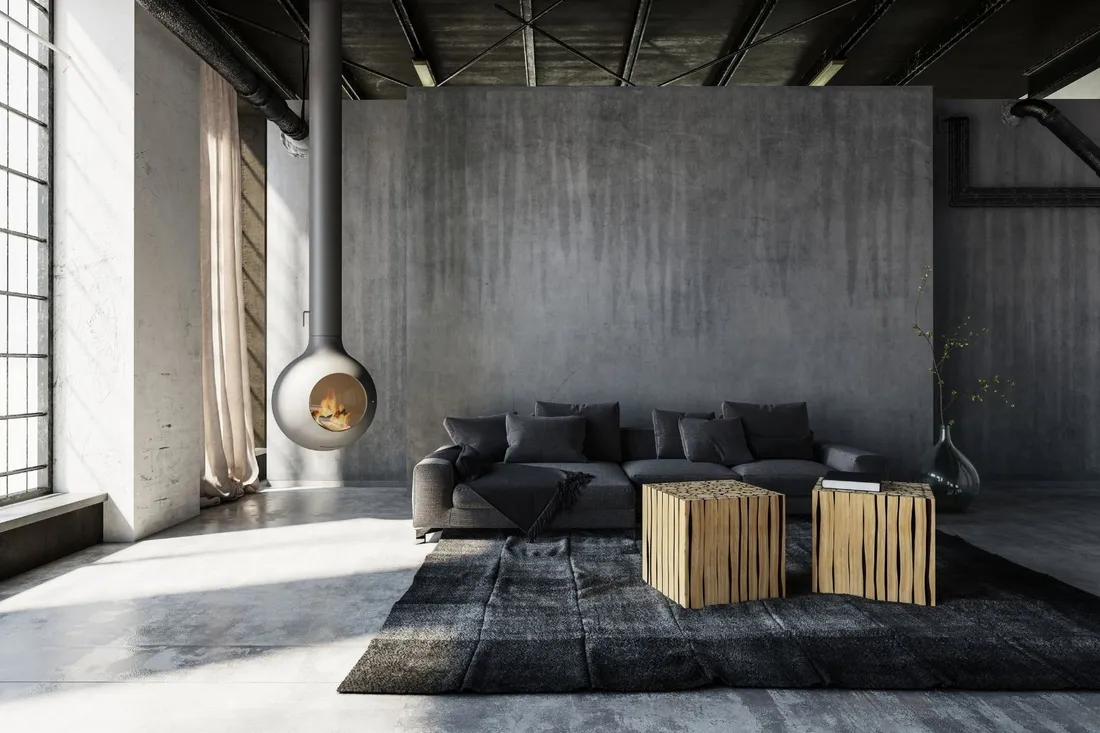 Loftowy salon z betonową ścianą, wiszącym kominkiem i ciemną sofą