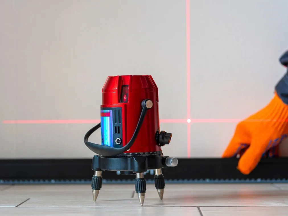 Laser krzyżowy na podłodze wyznacza linię podczas prac wykończeniowych